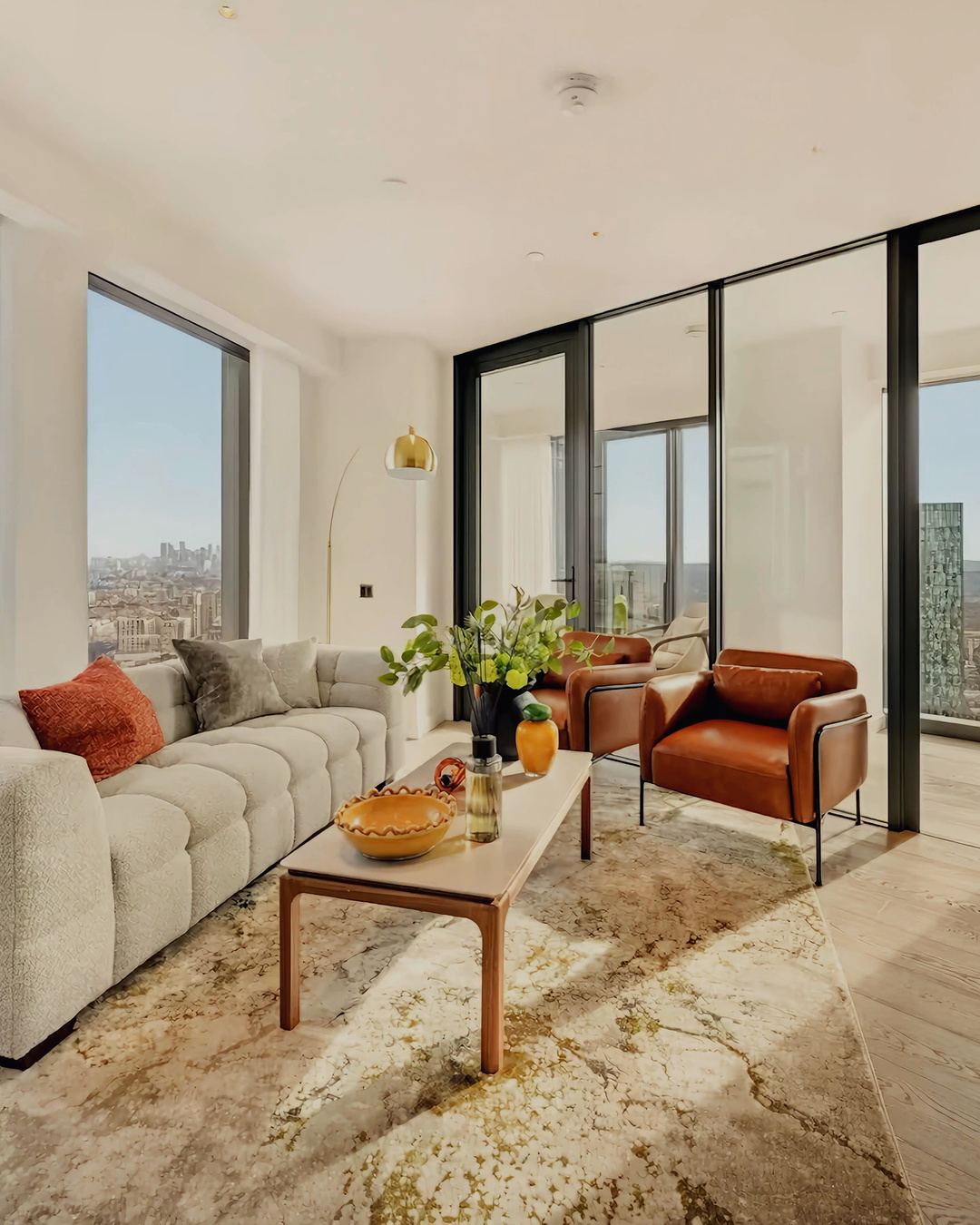 Living room with sofa, leather armchairs and skyline view