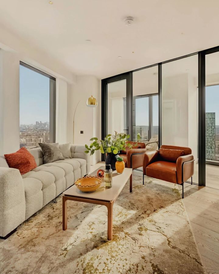 Living room with sofa, leather armchairs and skyline view